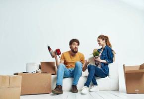 homme et femme asseoir sur blanc canapé des boites avec en mouvement mode de vie des choses photo