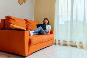 de bonne humeur femme bavardage sur le Orange canapé avec une portable les technologies photo