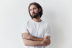 portrait de une homme avec une noir épais barbe et longue cheveux dans une blanc T-shirt sur une blanc isolé Contexte mode de vie sans pour autant pathétique tous les jours image photo