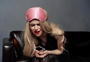 ivre blond femme dans sommeil masque avec mobile téléphone la photographie modèle photo