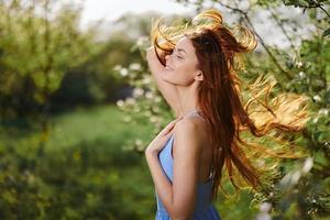 femme avec une magnifique sourire avec les dents et longue cheveux dans le printemps le coucher du soleil dans la nature dans le parc près le floraison des arbres bonheur, Naturel beauté et cheveux santé photo