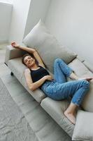 Jeune femme avec court la Coupe de cheveux cheveux ayant amusement à Accueil sur le canapé sourire et bonheur, vacances à maison, Naturel posant sans pour autant filtres, gratuit copie espace photo