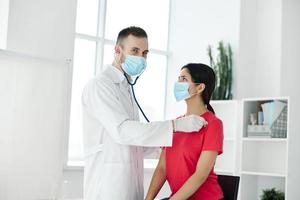 médecin examine femme dans médical masque rouge T-shirt stéthoscope photo