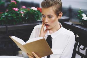 étudiant avec une livre dans le sien mains en train de lire marcher dans le Frais air éducation photo