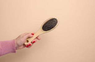 une femme main détient une brosse pour ratissage animal cheveux sur une beige Contexte photo