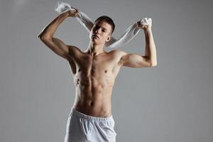 athlétique gars en portant les serviettes derrière le sien tête dans blanc short pompé en haut faire des exercices corps photo