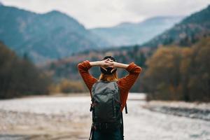 femme sur le rivière banque avec sac à dos Voyage randonnée montagnes dans le distance photo