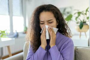 malade désespéré asiatique femme a grippe. rhinite, froid, maladie, allergie concept. jolie malade femme a courir nez, frotte nez avec mouchoir. éternuements femme. brunette éternuements dans une tissu photo