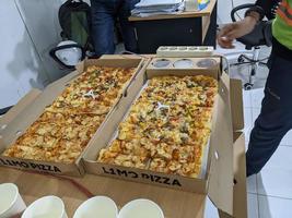 le longue façon Pizza lorsque objectif fête sur le bureau. photo