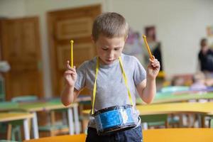 peu garçon pièces une jouet tambouriner. talentueux garçon futur musicien photo