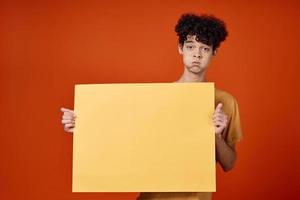 gars avec frisé cheveux Jaune affiche dans mains studio La publicité photo