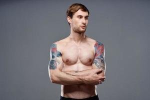 homme avec tatouages sur le sien bras pompé en haut torse faire des exercices tondu vue bodybuilder photo