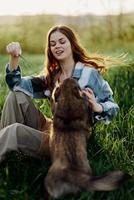 content femme séance dans la nature et en jouant avec sa animal de compagnie dans le parc séance sur le vert herbe photo