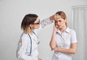 médecin femme les mesures le Température de le patient et une stéthoscope sur le cou photo