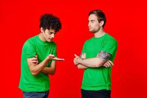 deux Hommes dans vert t-shirts supporter suivant à la communication relation amicale rouge Contexte photo