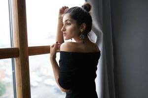 magnifique femme près fenêtre posant attrayant Regardez des boucles d'oreilles mode modèle photo