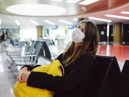 femme attendre pour une vol à le aéroport Jaune sac à dos médical masque photo