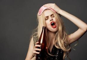 ivre femme avec une bouteille de Bière brillant maquillage blond rose masque pour sommeil photo