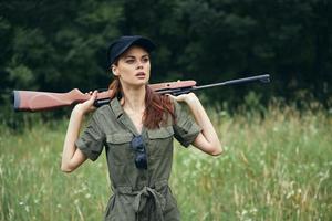 femme en portant une arme derrière le sien tête Frais air Voyage chasse Frais air vert des arbres photo