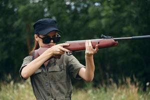 militaire femme chasse avec fusil à pompe des lunettes de soleil vert feuilles photo