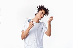 émotif gars avec frisé cheveux dans écouteurs écoute à la musique amusement photo