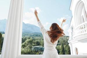 jolie femme longue cheveux dans une blanc peignoir de bain rester sur le balcon dans une Hôtel Montagne vue photo