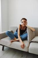 Jeune femme avec court la Coupe de cheveux cheveux ayant amusement à Accueil sur le canapé sourire et bonheur, vacances à maison, Naturel posant sans pour autant filtres, gratuit copie espace photo