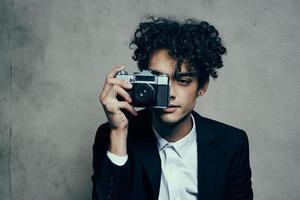 photographe avec une caméra dans une classique costume frisé cheveux studio modèle photo