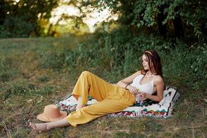 Jeune magnifique hippie femme mensonge sur le sol dans la nature dans le tomber dans éco vêtements dans Jaune un pantalon dans le le coucher du soleil lumière photo