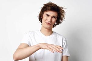 de bonne humeur gars avec ébouriffé cheveux dans une blanc T-shirt émotions fermer photo