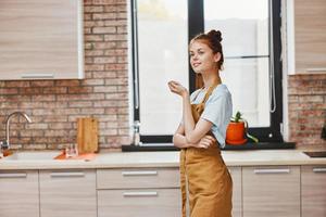 jolie femme gestes avec le sien mains dans une marron tablier cuisine intérieur mode de vie photo