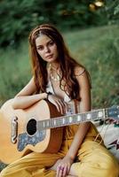content hippie femme avec une guitare sourit séance dans la nature par le Lac photo