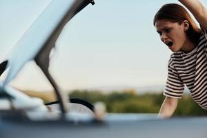 le femme ouvert le tronc et a crié avec colère. voiture panne sur le route dans la nature photo