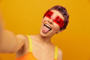 femme portant inhabituel millénaire des lunettes prise selfies dans tenue de sport contre un Orange studio arrière-plan, gratuit espace photo