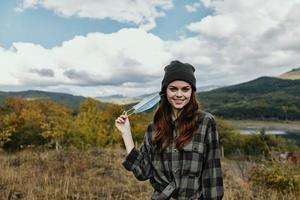 content femme dans une plaid chemise dans le l'automne forêt avec une médical masque sur sa visage photo