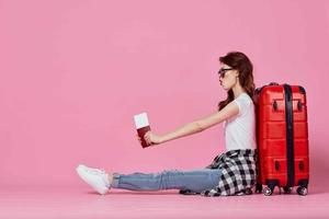 femme touristique rouge valise passeport et avion des billets rose Contexte photo
