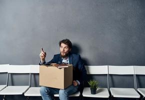 une homme dans une costume est assis sur une chaise avec une boîte emploi chercher la dépression photo