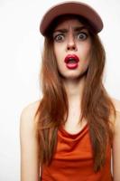 portrait de une femme dans une casquette surpris Regardez ouvert bouche Orange robe photo