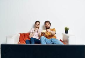 une homme et une femme sur le canapé en train de regarder le la télé à l'intérieur en train de regarder le spectacle photo