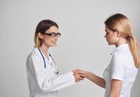 professionnel médecin femme et patient secouer mains sur une lumière Contexte photo