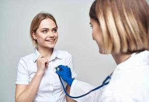 médecin avec une stéthoscope et une content patient sur une lumière Contexte photo