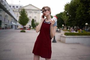 femme sur le rue parlant sur le téléphone portant des lunettes verre avec boisson mode photo