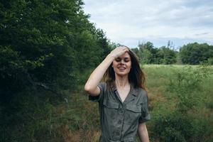 femme dans le Prairie dans vert combinaison se redresse sa cheveux avec une tondu Regardez Frais air photo