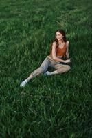 une femme mensonges sur Frais printemps vert herbe dans une parc sans pour autant les moustiques ou tiques et jouit relaxant tandis que en train de regarder le le coucher du soleil. le concept de sûr Extérieur des loisirs photo