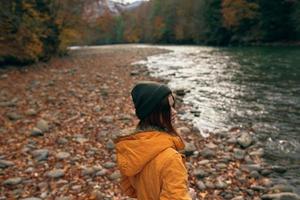 femme dans l'automne vêtements sur la nature près le rivière marcher le montagnes photo