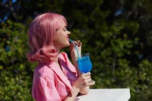 de bonne humeur femme dans rose robe en plein air avec cocktail content femelle relaxant photo