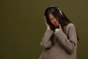 brunette dans une chandail écoute à la musique avec écouteurs amusement studio modèle photo