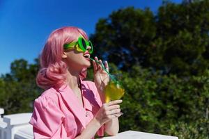 Enchanté Jeune fille dans rose robe en plein air avec cocktail relaxation concept photo