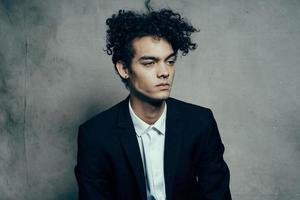 frisé aux cheveux gars dans une costume séance sur une chaise mode moderne style veste photo