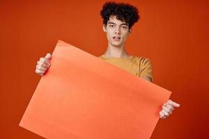 émotif gars avec frisé cheveux île dans mains La publicité rouge Contexte photo